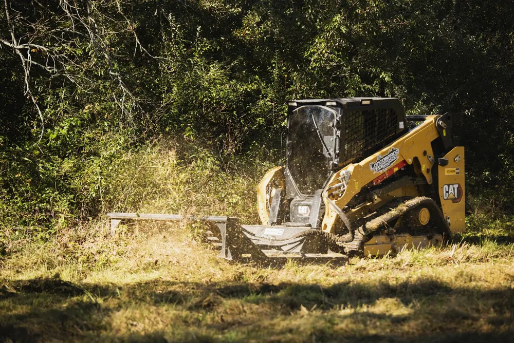 Skid steer with forestry mulching attachment clearing brush